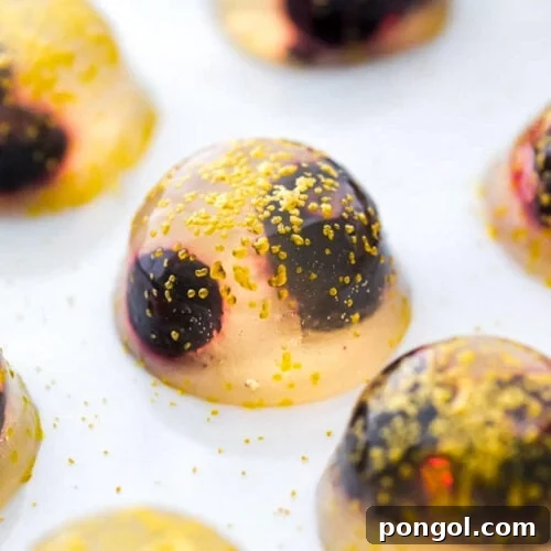 A close-up of a single champagne jello shot on a plate.