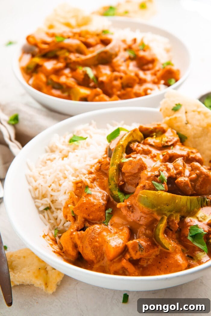 Angled photo of Instant Pot chicken tikka masala in a bowl with basmati rice and naan