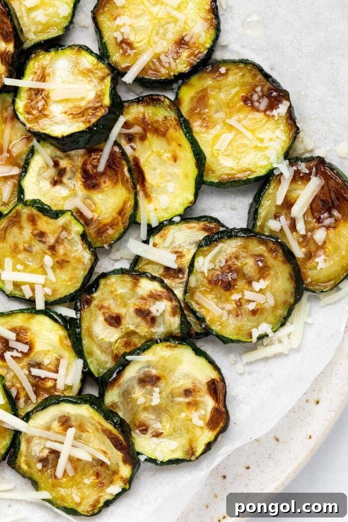 Crispy Air Fryer Zucchini 2 Overhead image of perfectly air fried zucchini slices with a generous sprinkle of parmesan cheese on top, ready to be served.