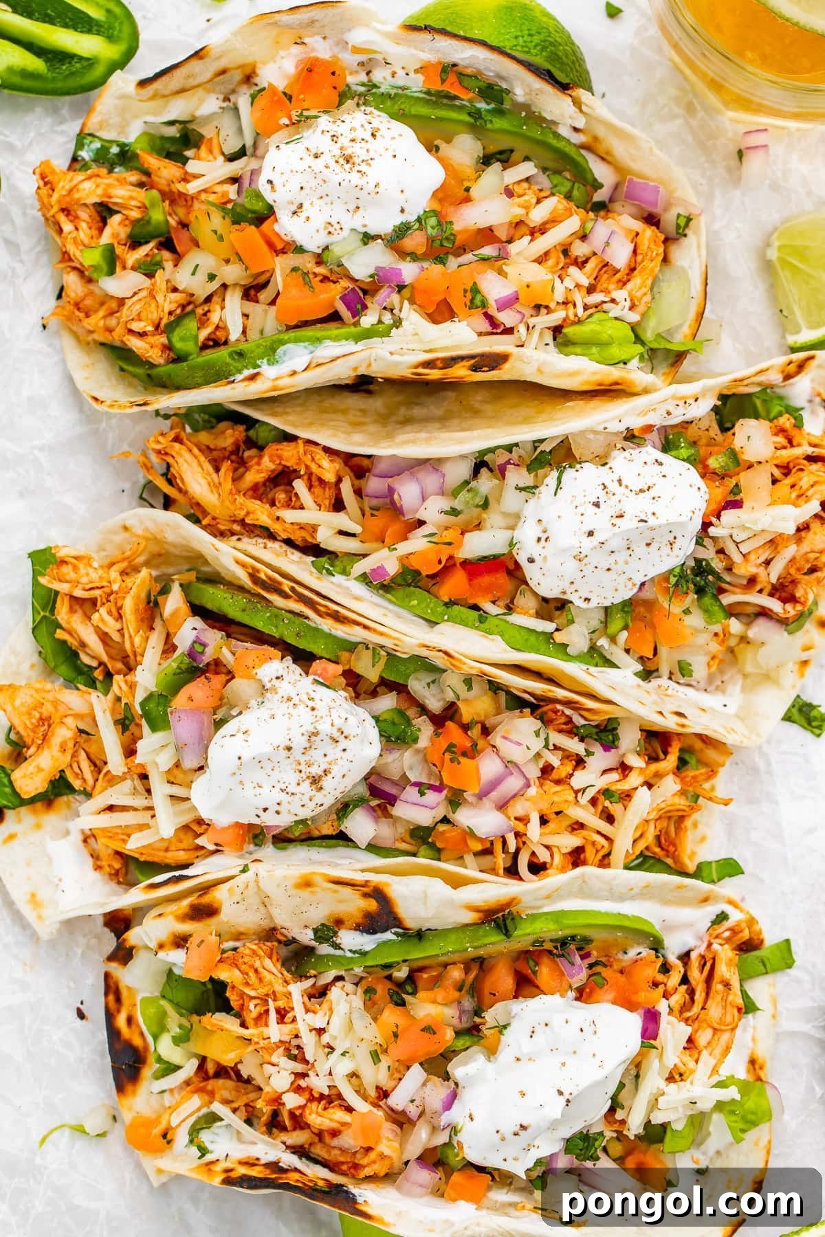 Four chicken tacos in a row, beautifully arranged and ready to be served.