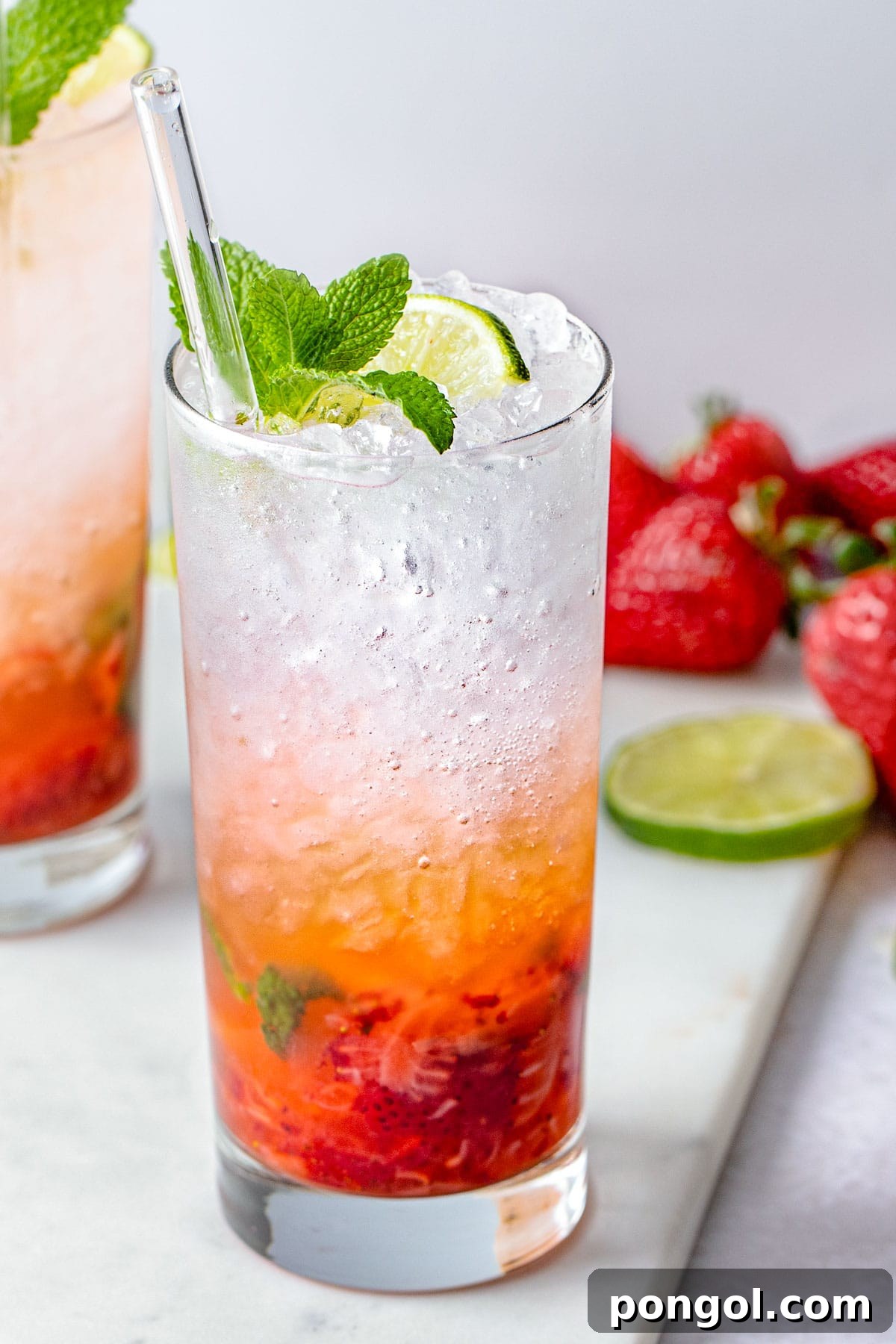 Ruby Mint Breeze 3 A tall highball glass containing a strawberry mojito, with rum and ice layer on top of muddled strawberries and mint.