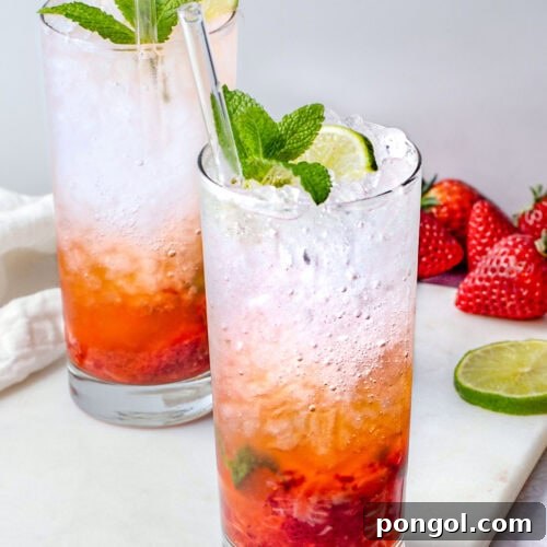 Ruby Mint Breeze 4 A tall highball glass containing a strawberry mojito, with rum and ice layer on top of muddled strawberries and mint.