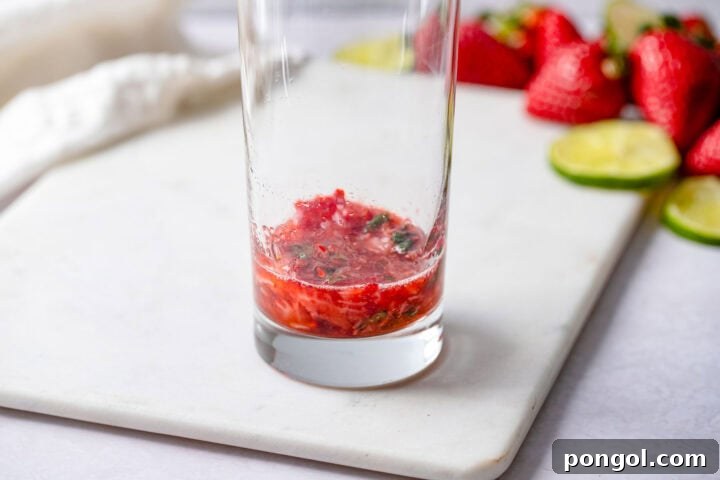 Ruby Mint Breeze 6 Muddled strawberries and mint leaves in the bottom of a highball glass.