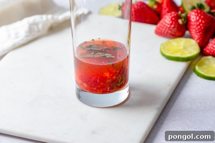 Ruby Mint Breeze 7 Lime juice and rum in a highball glass with muddled strawberries and mint leaves.