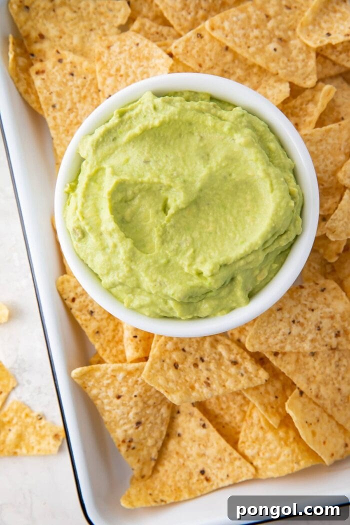 Guacamole dip in a bowl on a platter with tortilla chips