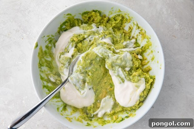 Ingredients for guacamole dip in bowl with spoon