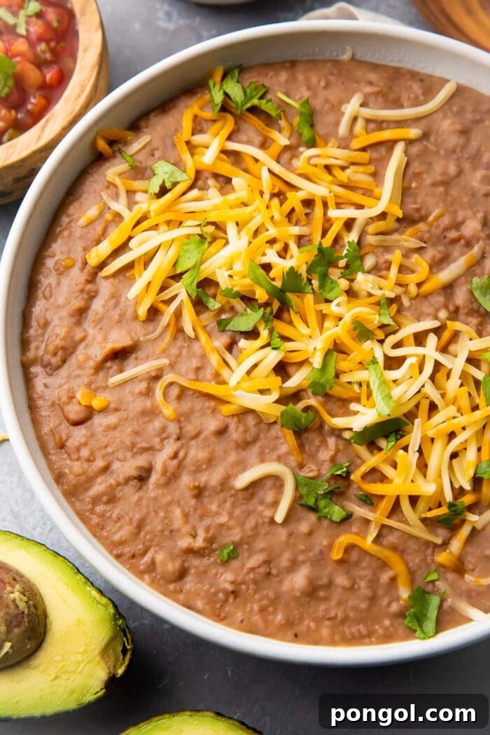 Instant Pot refried beans in a bowl topped with shredded cheese, looking rich and creamy.