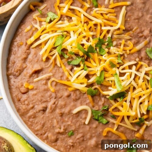 Instant Pot refried beans in a bowl topped with shredded cheese