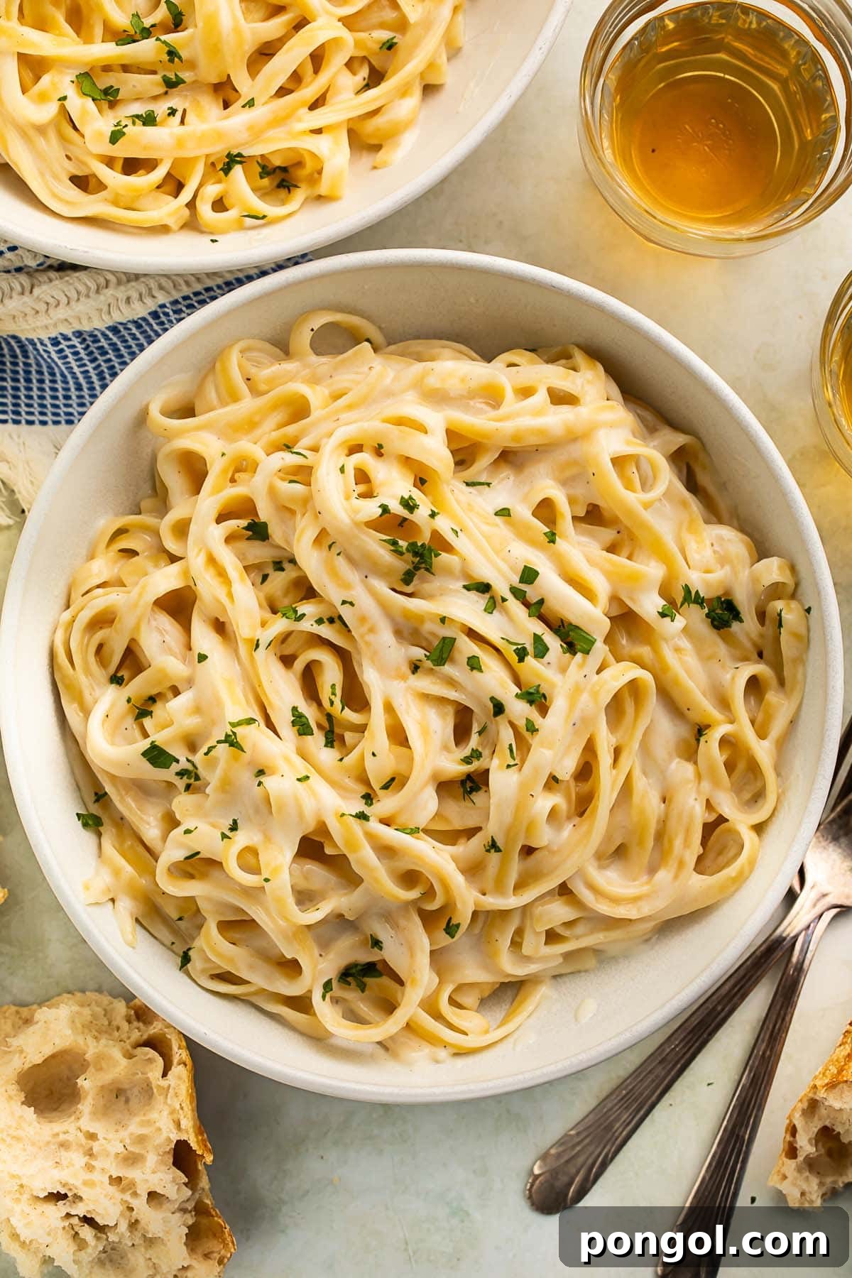 A bowl of creamy cottage cheese alfredo on fettuccine garnished with chopped parsley, showcasing a healthy yet decadent pasta dish.