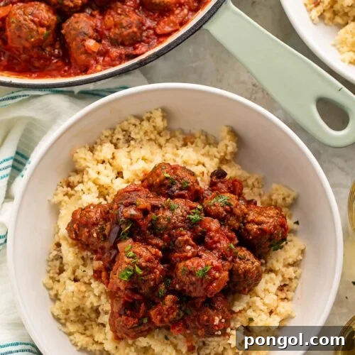 Moroccan meatballs served over a bed of fluffy couscous in a large white bowl.