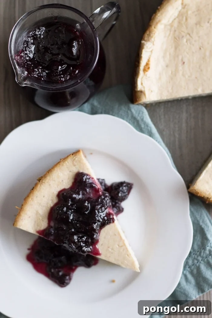 A slice of Vegan Lemon Ricotta Cheesecake adorned with a vibrant Blueberry White Wine Sauce, perfect for any celebration