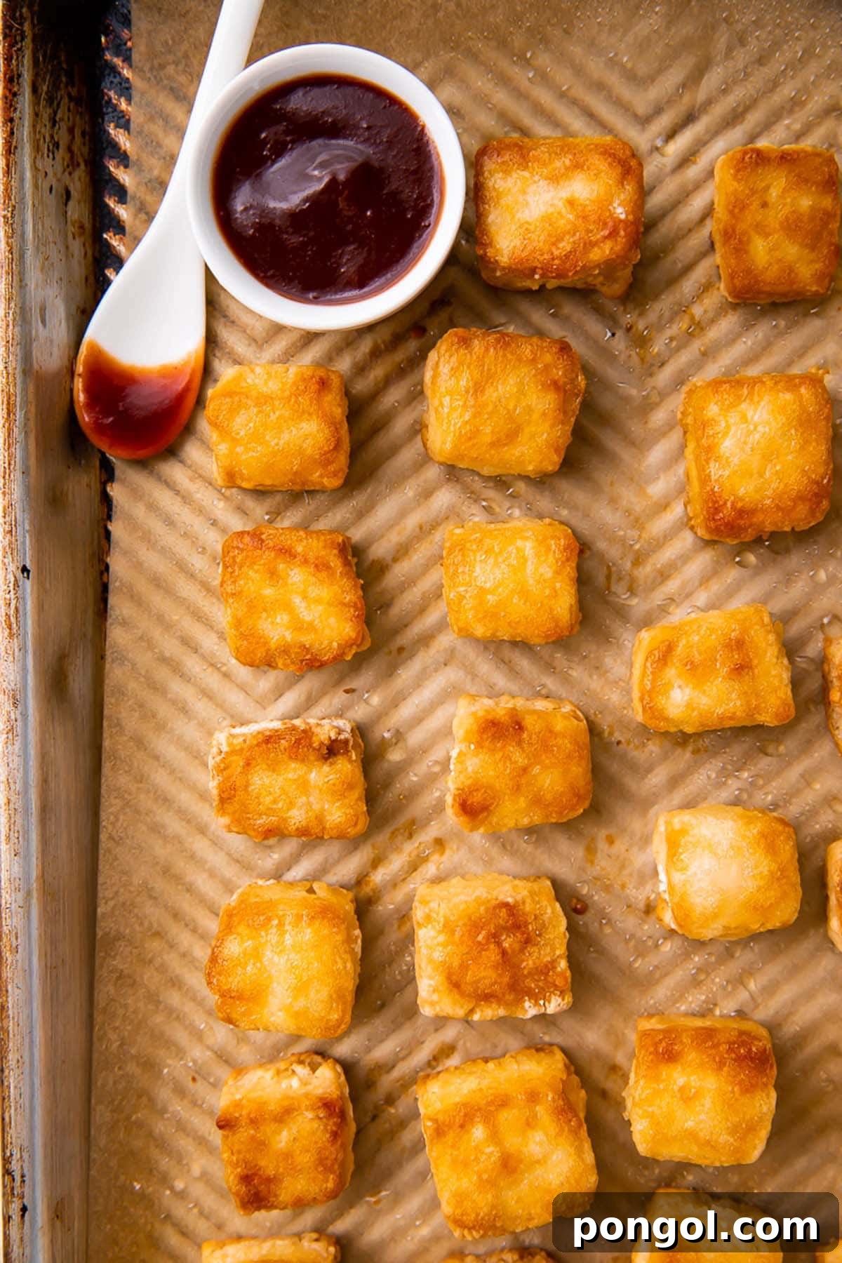 Crispy baked tofu cubes evenly arranged on a baking sheet, ready for the oven.