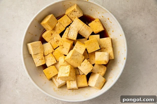 Tofu cubes marinating in a bowl.