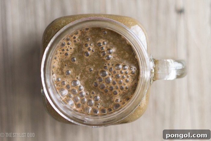 Closeup of Brownie Batter Green Smoothie in a glass with straw.