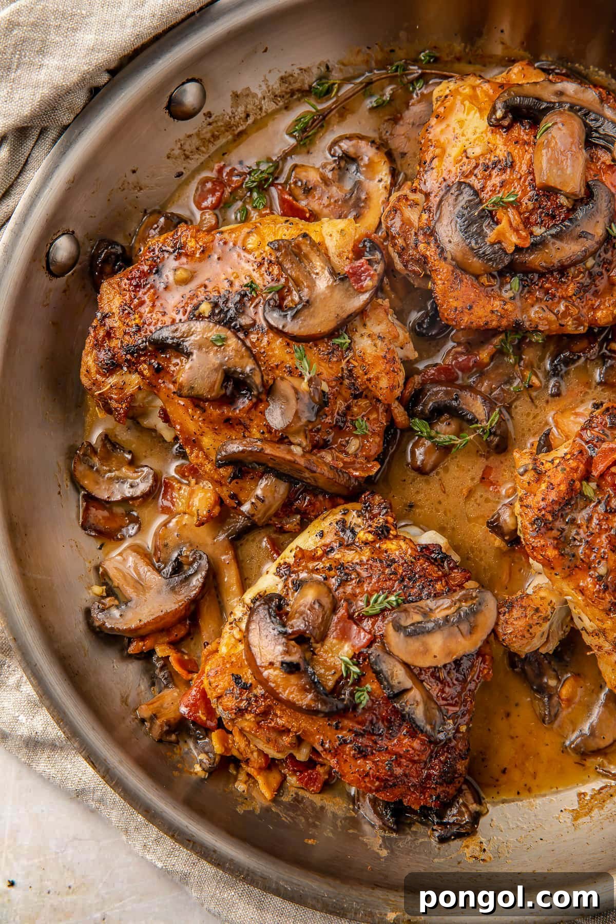 125 Simple Chicken Dinners: Fast Meals with Pantry Staples 101 Creamy Whole30 bacon mushroom chicken thighs in a large silver skillet.
