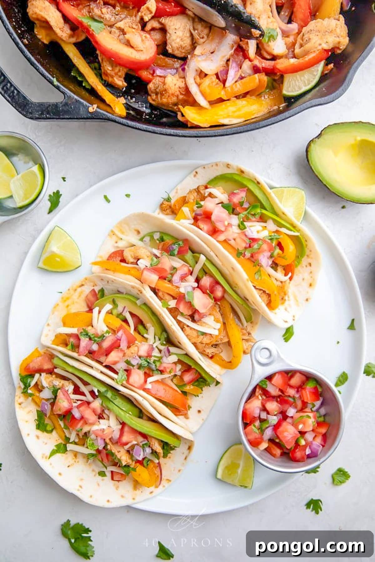 125 Simple Chicken Dinners: Fast Meals with Pantry Staples 103 Crockpot chicken fajitas, with 4 fajitas in flour tortillas lined up on a white plate with a small ramekin of pico de gallo.