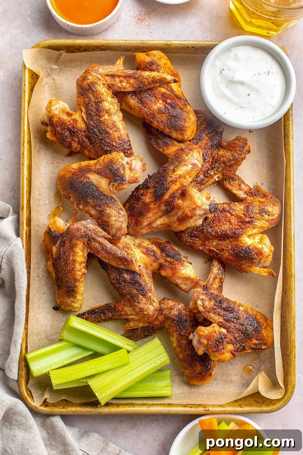 125 Simple Chicken Dinners: Fast Meals with Pantry Staples 110 Seasoned, baked crispy whole chicken wings on a sheet pan with celery sticks and a ramekin of ranch dressing.