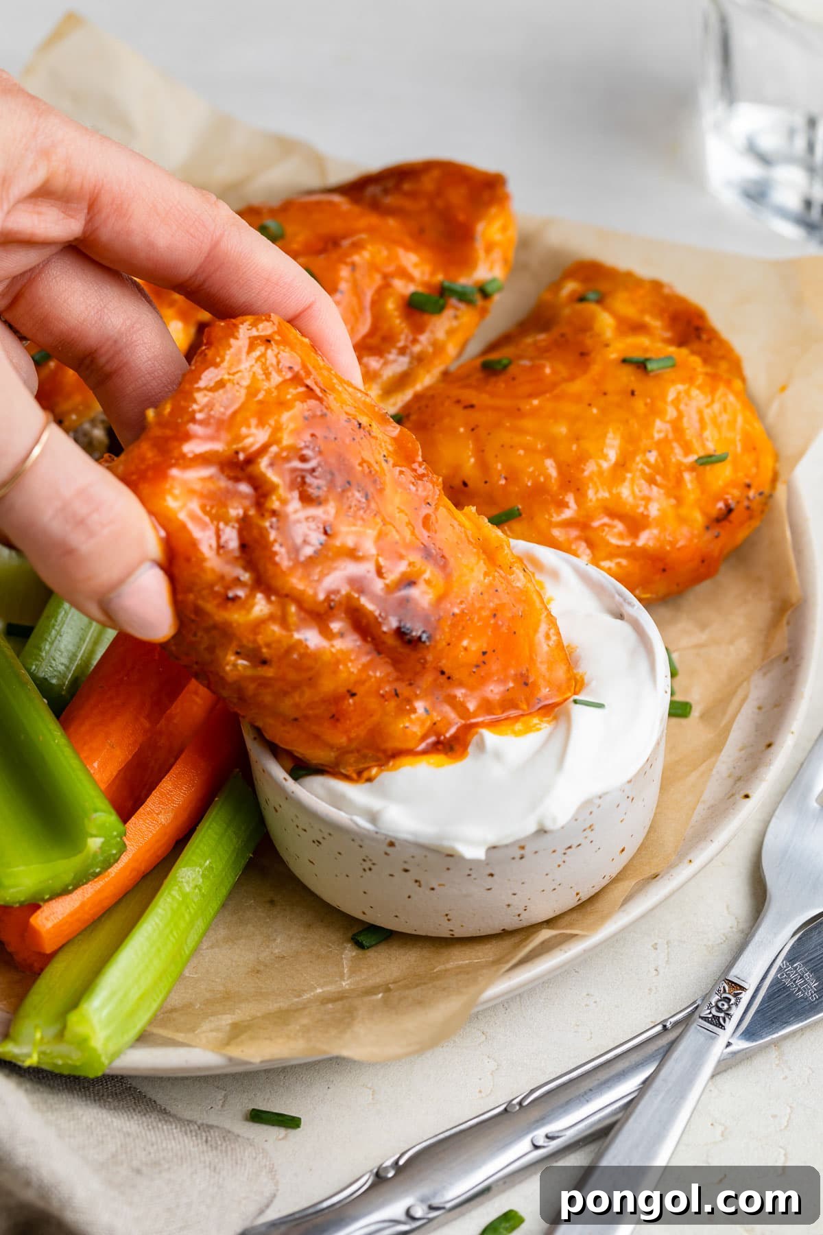 125 Simple Chicken Dinners: Fast Meals with Pantry Staples 117 A buffalo sauced chicken thigh being dipped into a bowl of blue cheese dressing.