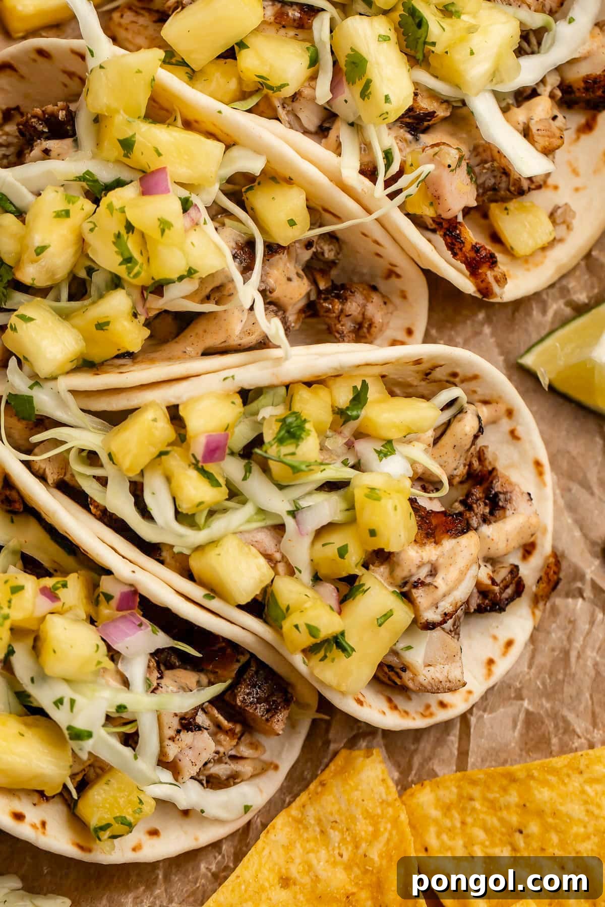 125 Simple Chicken Dinners: Fast Meals with Pantry Staples 123 Overhead photo showing 4 jerk chicken tacos lined up on a sheet of parchment paper with tortilla chips and mango salsa.