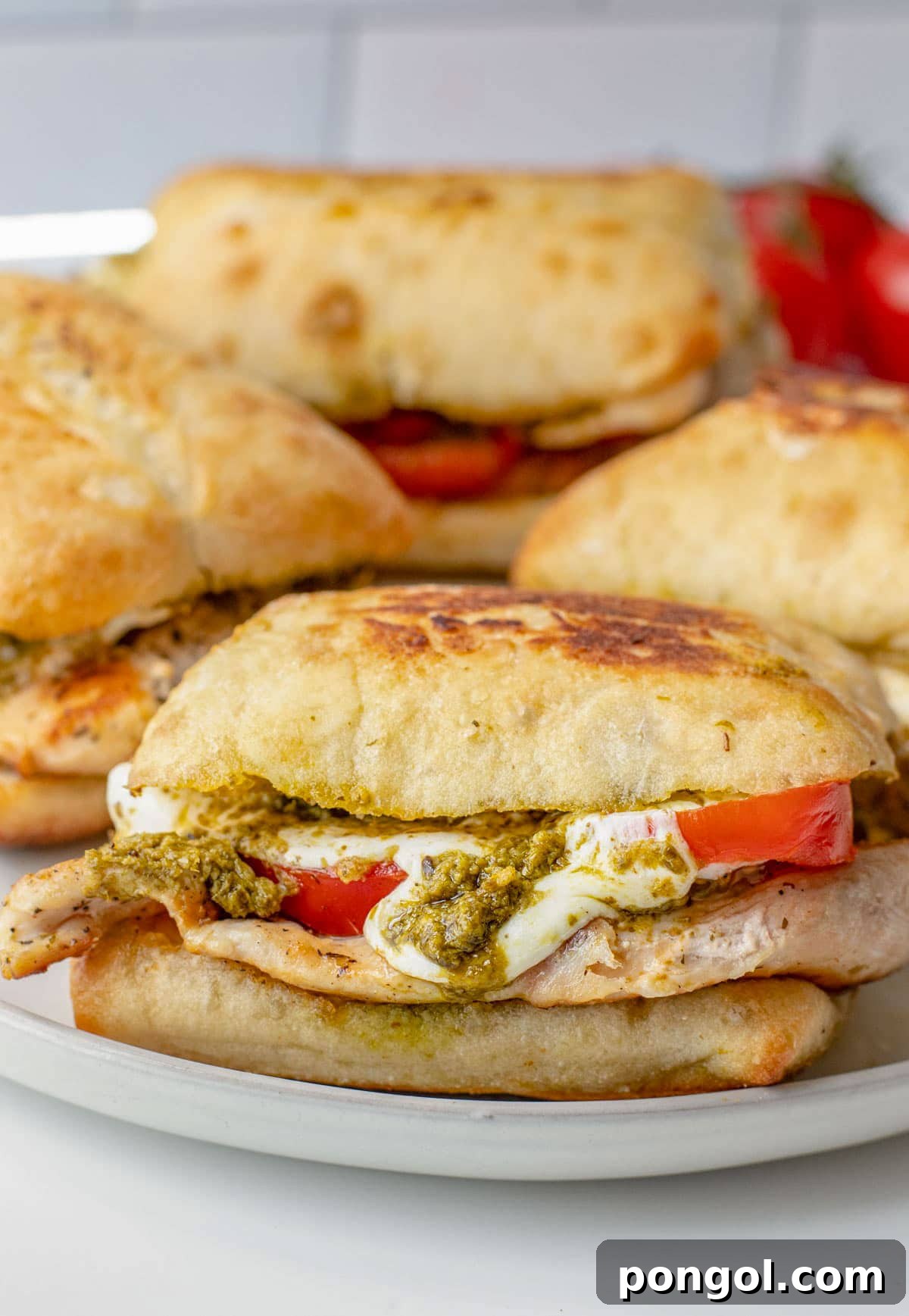 125 Simple Chicken Dinners: Fast Meals with Pantry Staples 14 4 chicken pesto sandwiches with tomato and cheese on a plate.