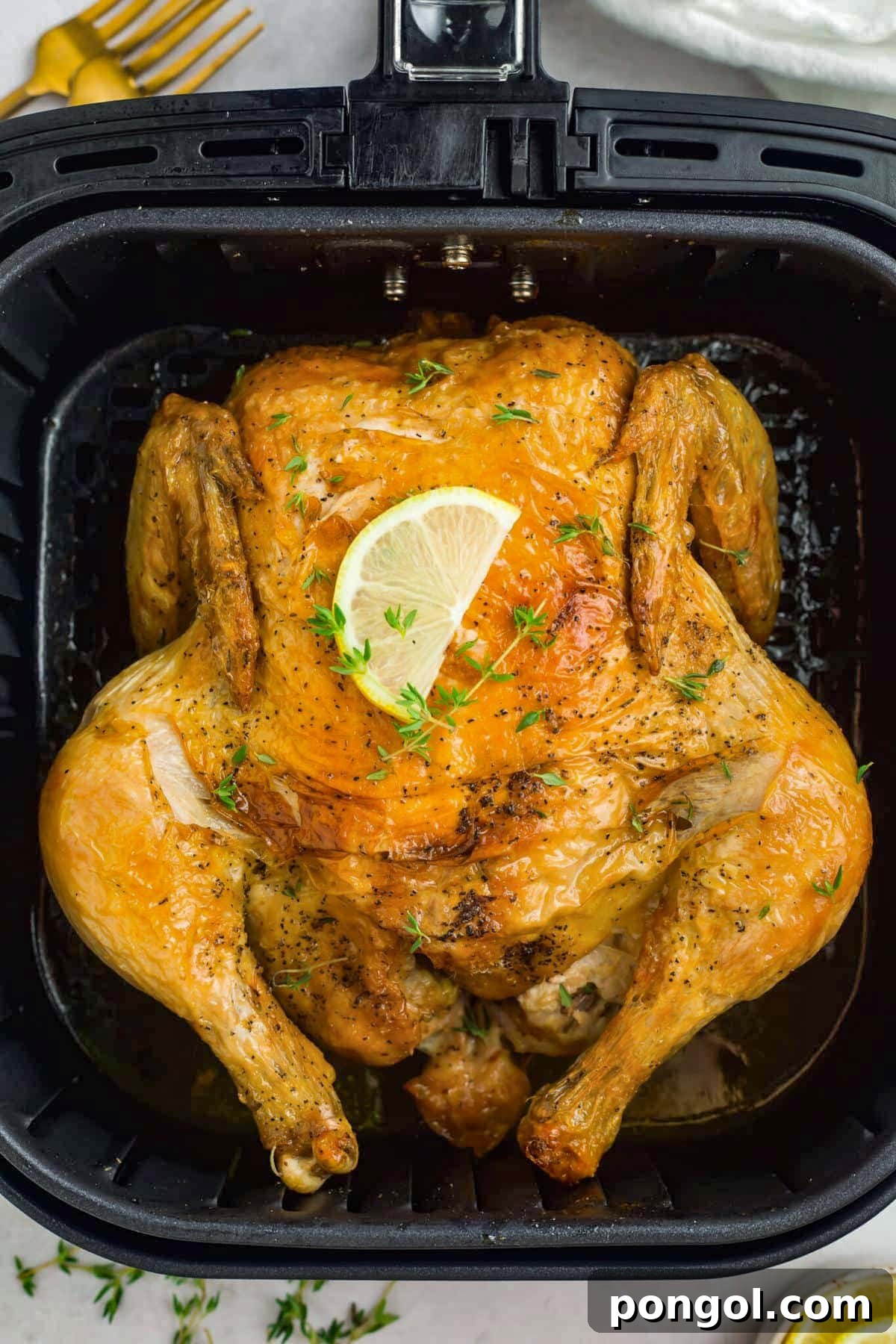 125 Simple Chicken Dinners: Fast Meals with Pantry Staples 15 Overhead view of a golden, herb-rubbed whole chicken cooked in an air fryer then topped with a lemon wedge.