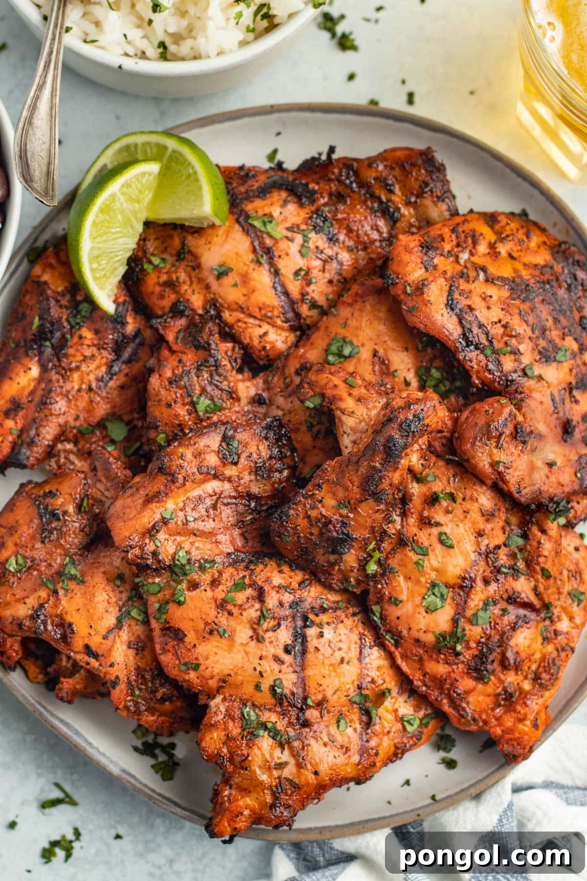 125 Simple Chicken Dinners: Fast Meals with Pantry Staples 16 Grilled achiote chicken piled on a large round plate with a lime wedge.
