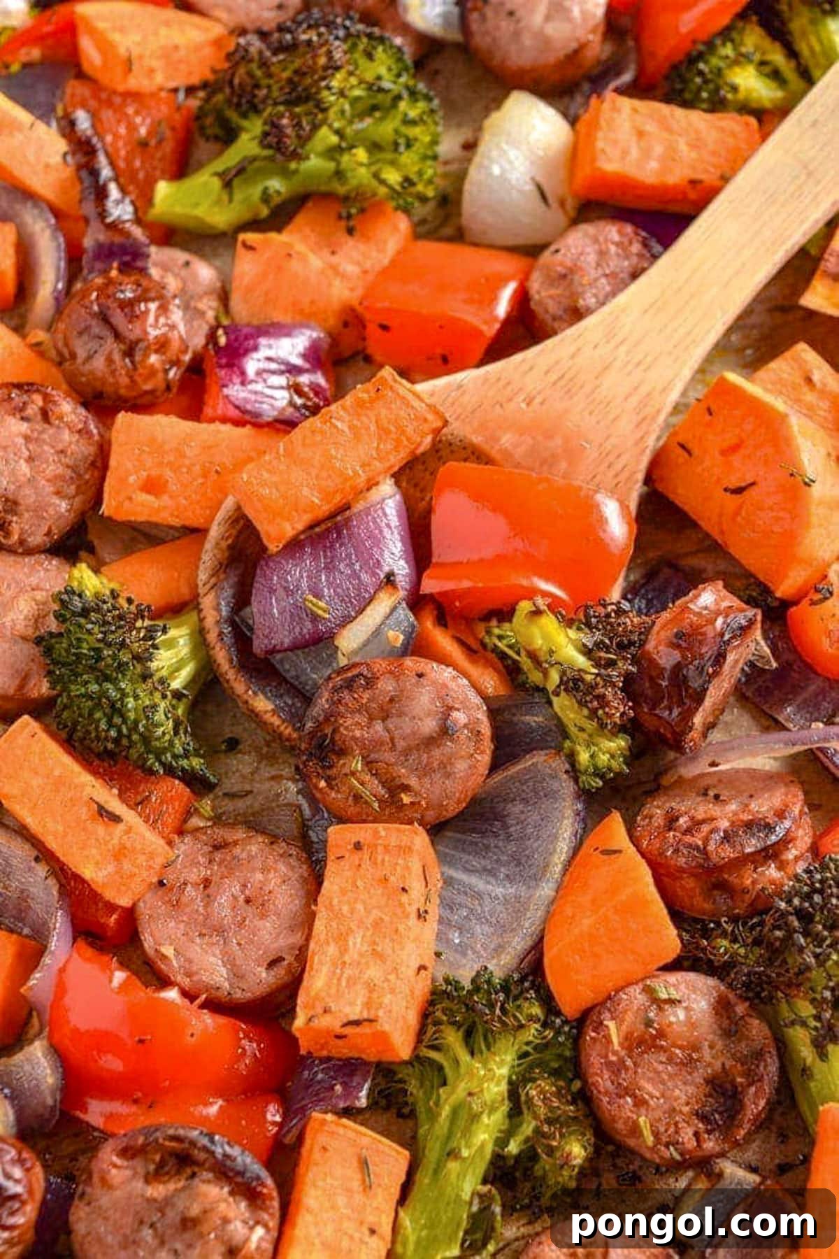 125 Simple Chicken Dinners: Fast Meals with Pantry Staples 28 Easy sheet pan chicken sausage and roasted vegetables on a sheet pan with a large wooden spoon.