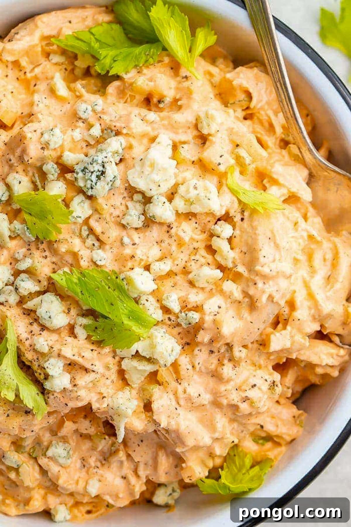 125 Simple Chicken Dinners: Fast Meals with Pantry Staples 30 A large bowl filled with creamy buffalo chicken salad topped with blue cheese crumbles and fresh herbs.