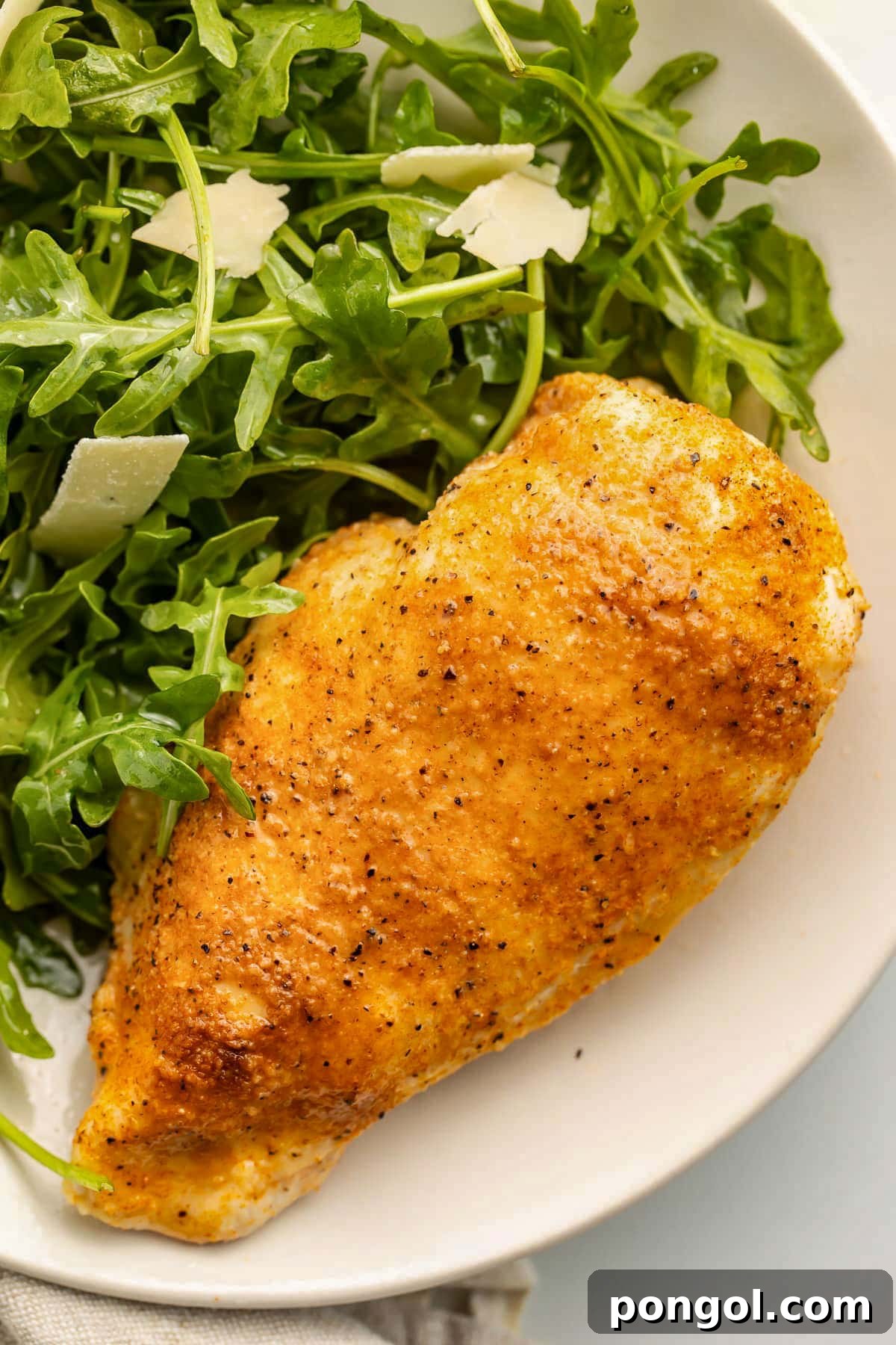 125 Simple Chicken Dinners: Fast Meals with Pantry Staples 4 A chicken breast, cooked in the Instant Pot, on a neutral plate with a small side salad.