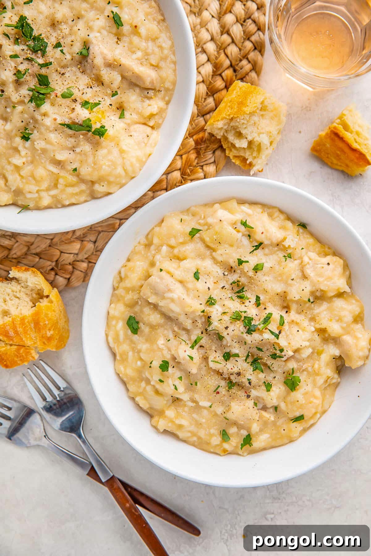 125 Simple Chicken Dinners: Fast Meals with Pantry Staples 32 Two white bowls holding Crockpot chicken and rice on a neutral table with woven rattan placemats.