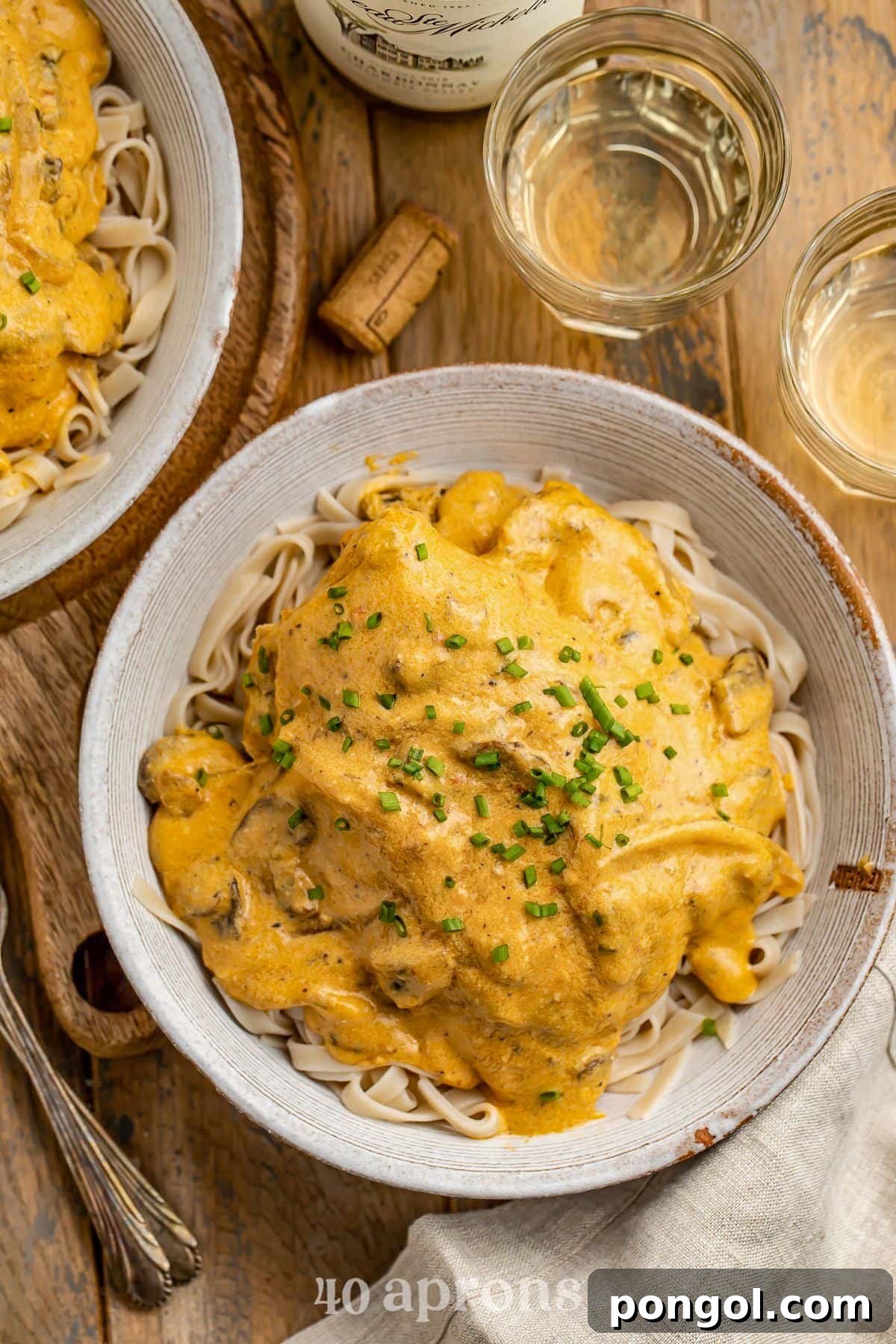 125 Simple Chicken Dinners: Fast Meals with Pantry Staples 40 A large bowl holding angel hair pasta topped with a Crockpot-cooked chicken breast and a rich sauce.