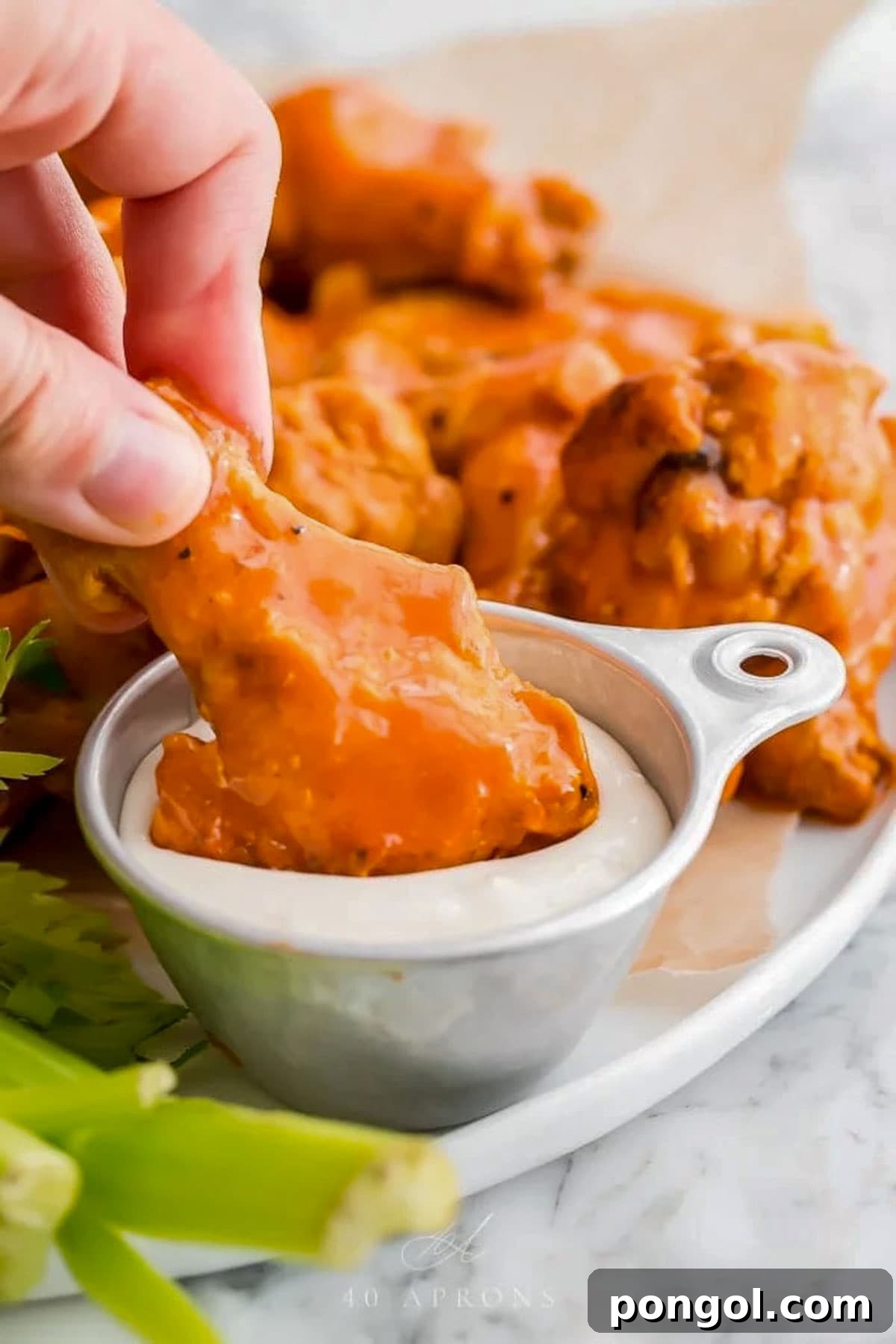 125 Simple Chicken Dinners: Fast Meals with Pantry Staples 52 Bright orange buffalo-sauced chicken wings, cooked in the Crockpot, being dipped into a small bowl of ranch dressing.
