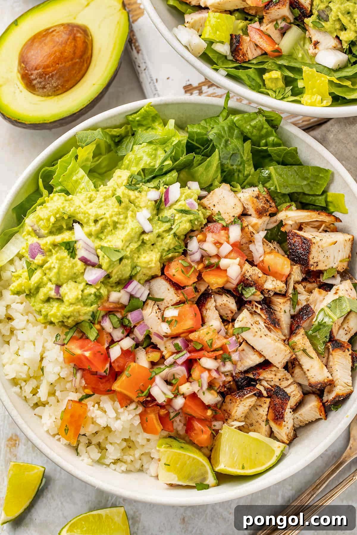 125 Simple Chicken Dinners: Fast Meals with Pantry Staples 63 Close-up of a loaded burrito bowl with cauliflower rice, easy guacamole, fresh pico, grilled chicken, and green lettuce.