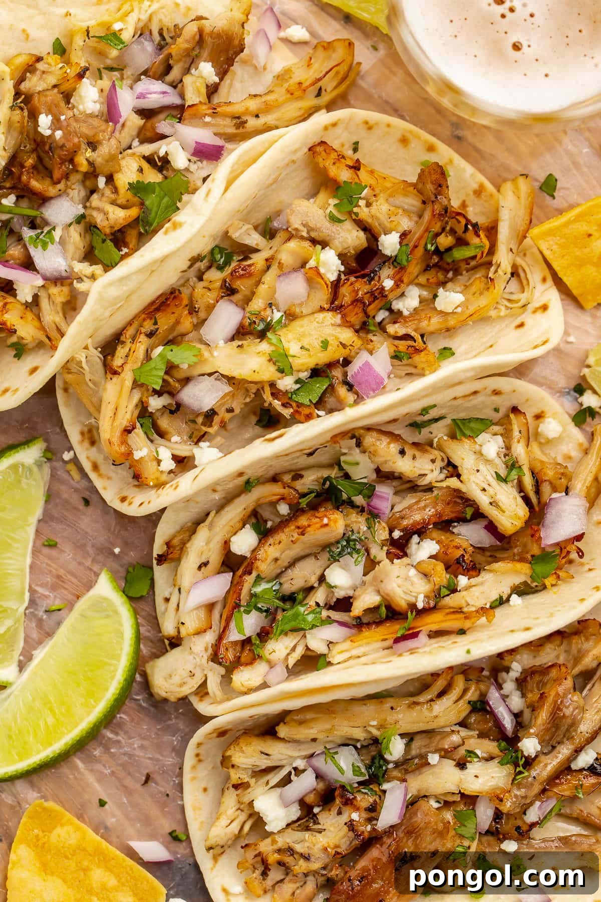 125 Simple Chicken Dinners: Fast Meals with Pantry Staples 65 Close-up of flour tortilla tacos holding chicken carnitas cooked in the Instant Pot.