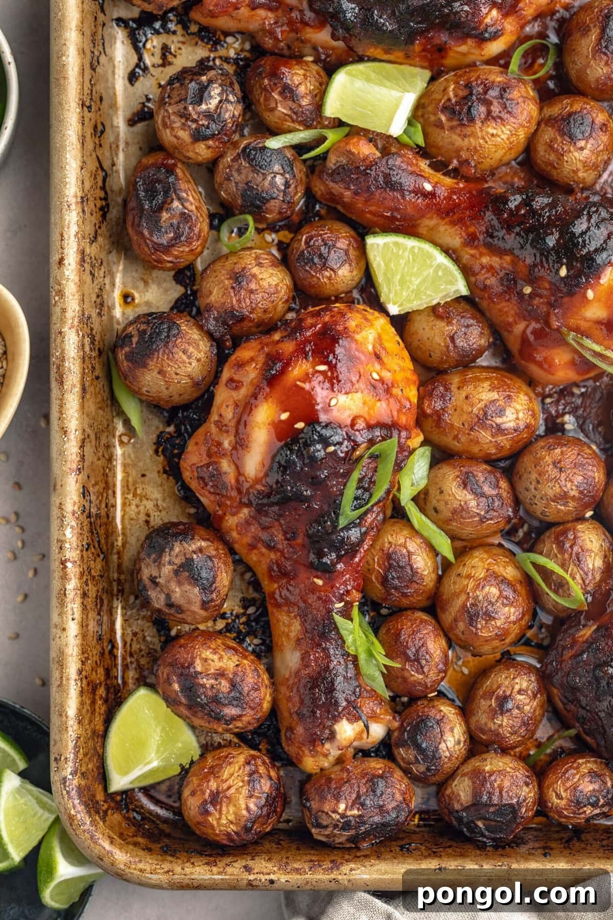 125 Simple Chicken Dinners: Fast Meals with Pantry Staples 72 A baking sheet holding sheet pan gochujang chicken with potatoes and lime wedges.