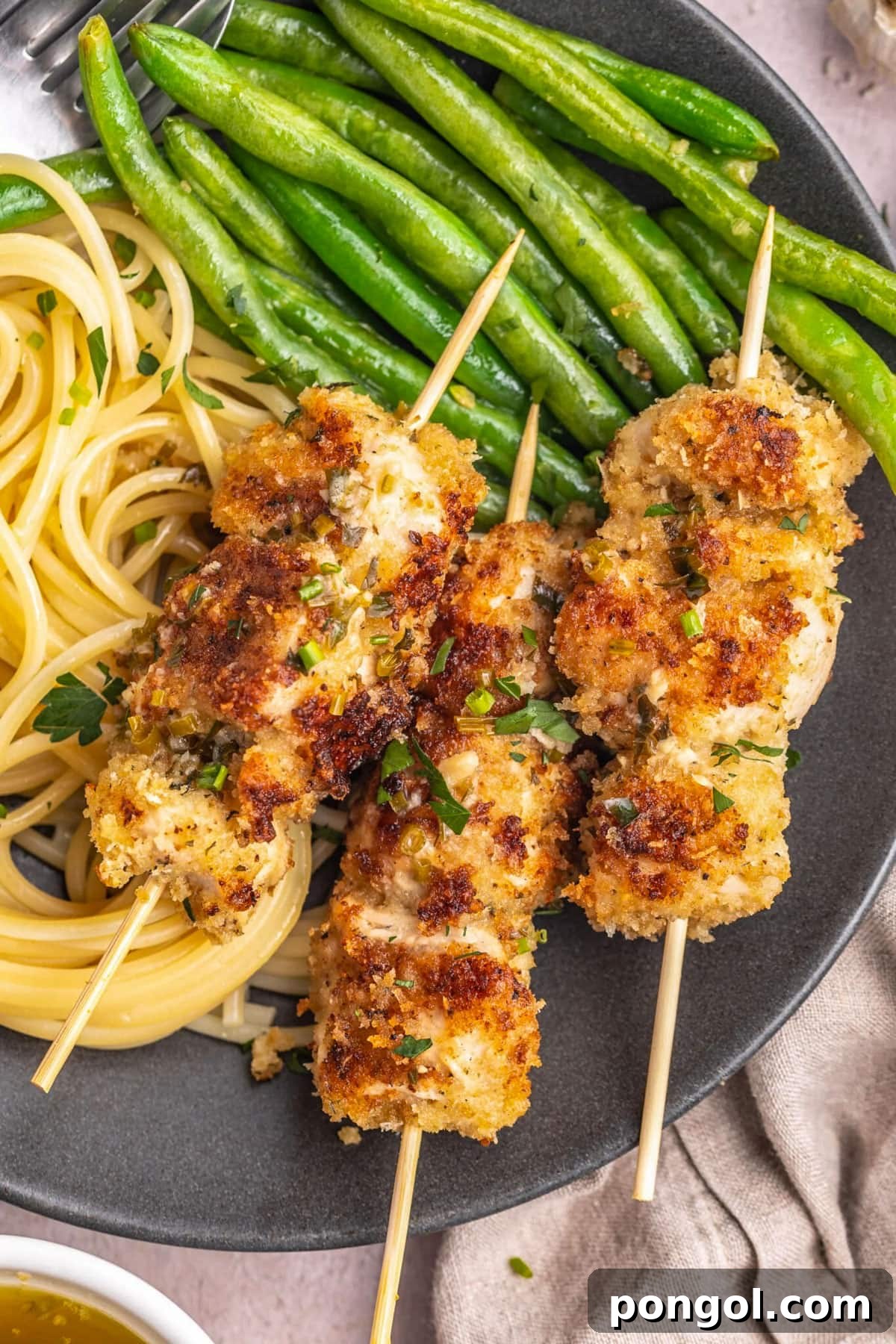 125 Simple Chicken Dinners: Fast Meals with Pantry Staples 73 Skewered chicken spiedini on a grey plate with bright green asparagus and thin pasta.