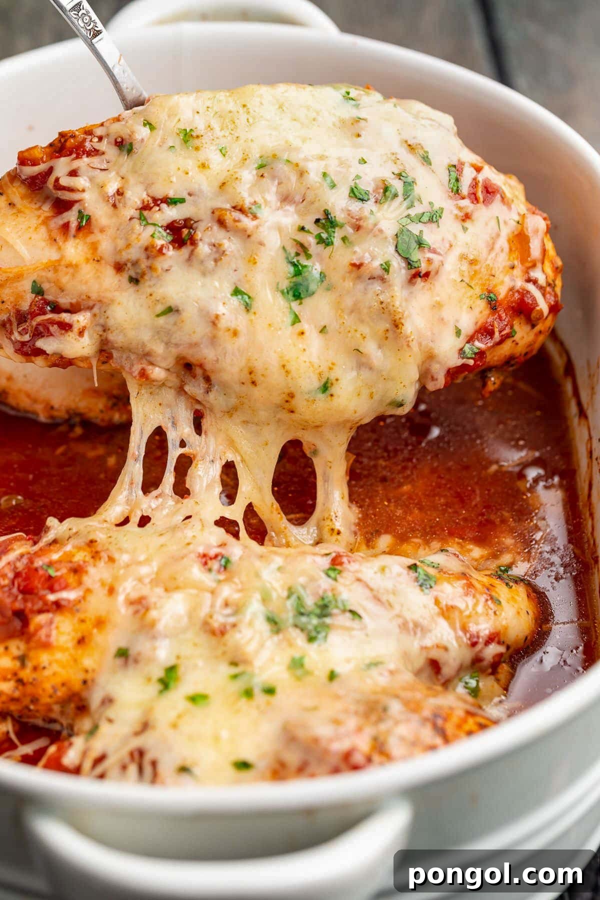 125 Simple Chicken Dinners: Fast Meals with Pantry Staples 88 A cheesy salsa chicken breast being lifted out of a casserole dish.