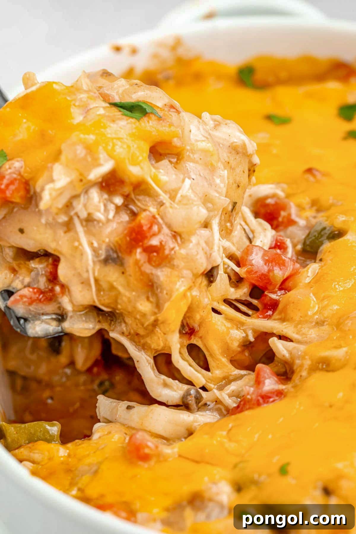 125 Simple Chicken Dinners: Fast Meals with Pantry Staples 95 A large scoop of cheesy chicken king ranch casserole being lifted out of a casserole dish with a large spoon.