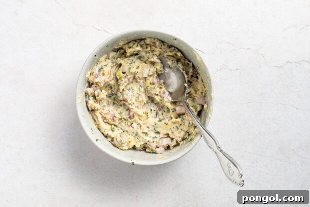 Mixing garlic-herb butter ingredients in a bowl.