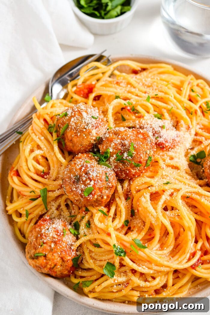 Instant pot meatballs served over spaghetti with a side of fresh parsley.
