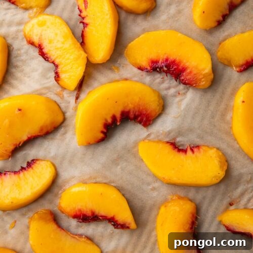 Peach wedges on a baking sheet lined with parchment paper