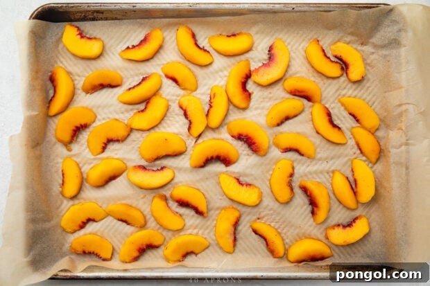 Unfrozen peach slices on a baking sheet lined with parchment paper