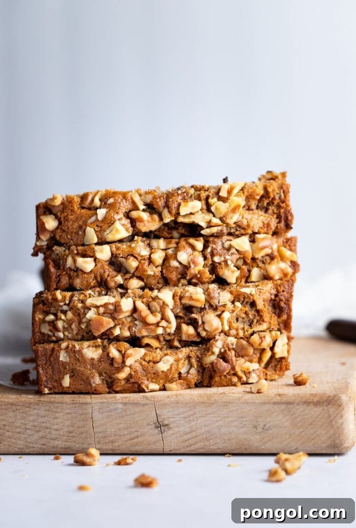 4 slices of vegan zucchini bread stacked on top of eachother in front of a light blue-grey background