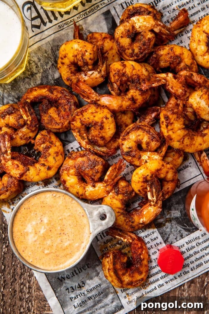 Easy Weeknight Blackened Shrimp 2 A pile of blackened shrimp on newspaper next to a dipping cup of remoulade sauce