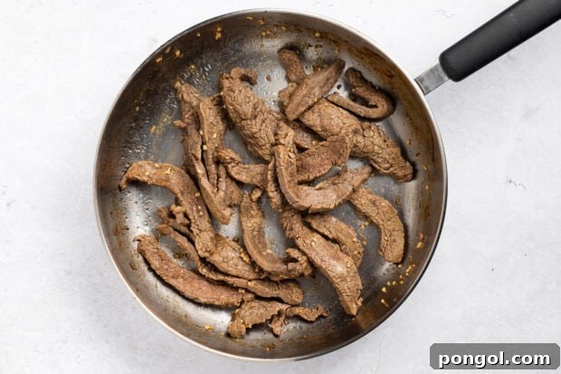 Wok-Tossed Beef Noodles 8 Beef strips sizzling in a hot wok or skillet, actively stir-frying until browned.