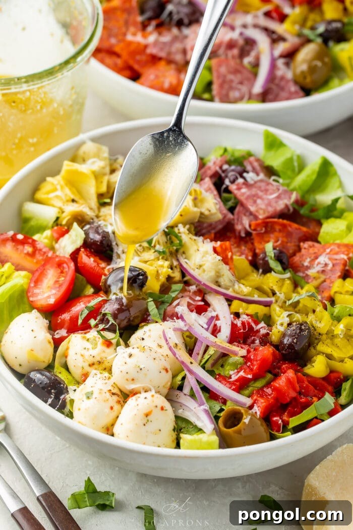 Effortless Antipasto Salad with Bright Italian Vinaigrette 3 Italian vinaigrette spooned over an antipasto salad in a large bowl.