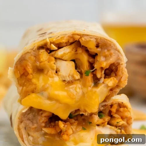 Two halves of a chicken burrito stacked on top of each other, showing a filling of chicken, rice, beans, and gooey cheese.