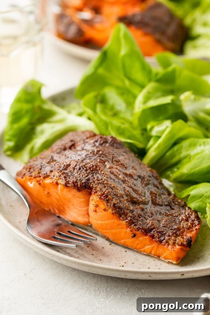 Air fryer salmon on a plate next to a small green salad