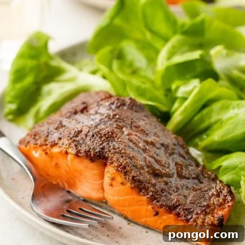 Air fryer salmon on a plate next to a small green salad