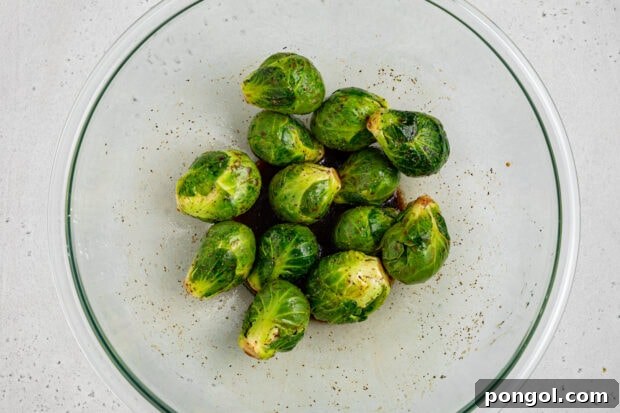 Brussels sprouts being tossed in a bowl with marinade.